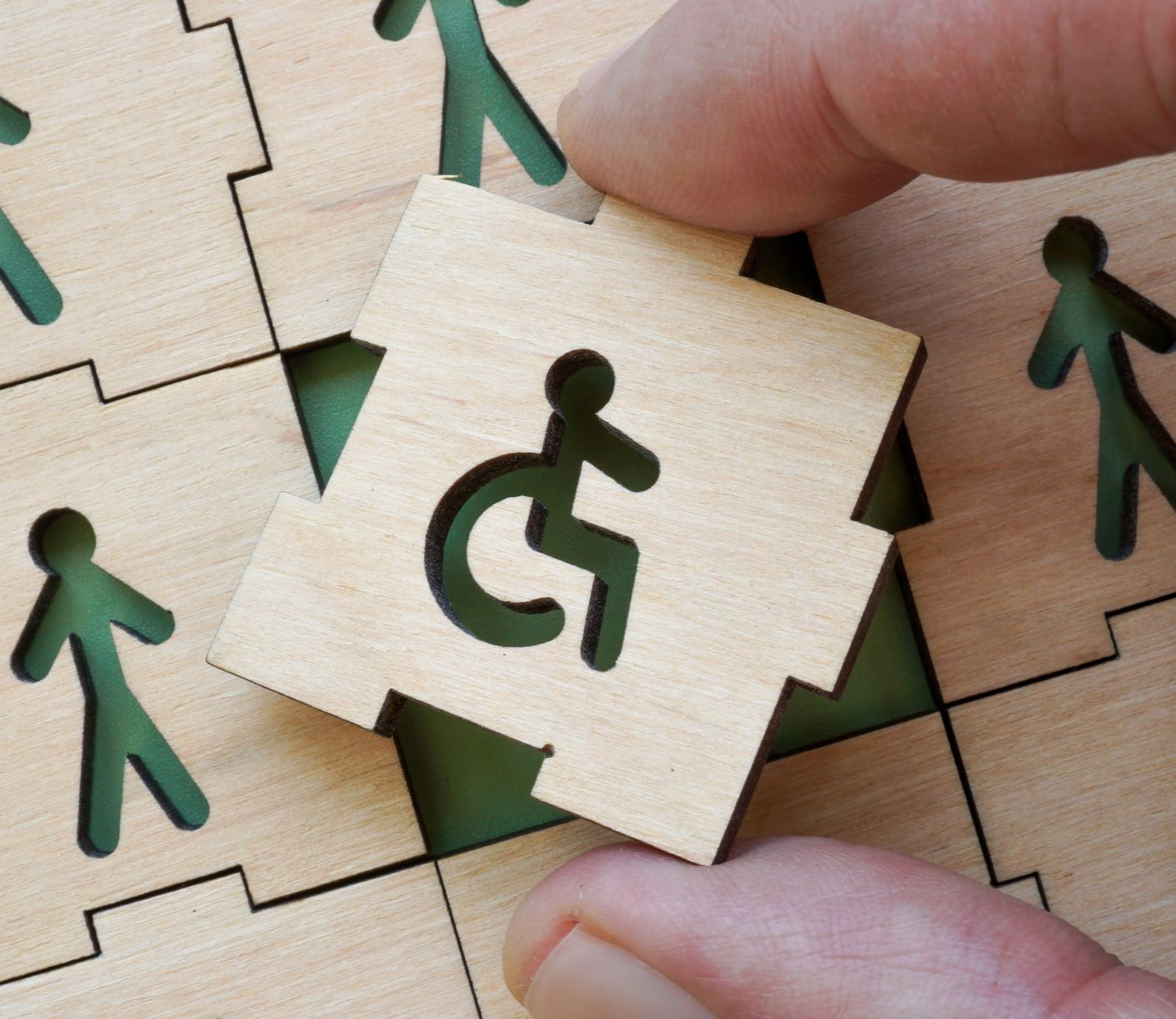 Pièce de puzzle en bois avec le dessin d'un bonhomme sur un fauteuil roulant