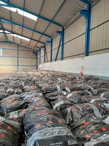 Un gran almacén lleno de montones de bolsas de carbón.