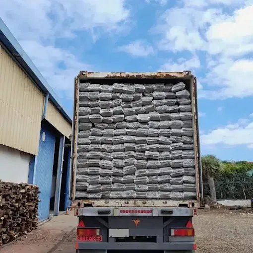 Un camión lleno de sacos de cemento está estacionado frente a un edificio.