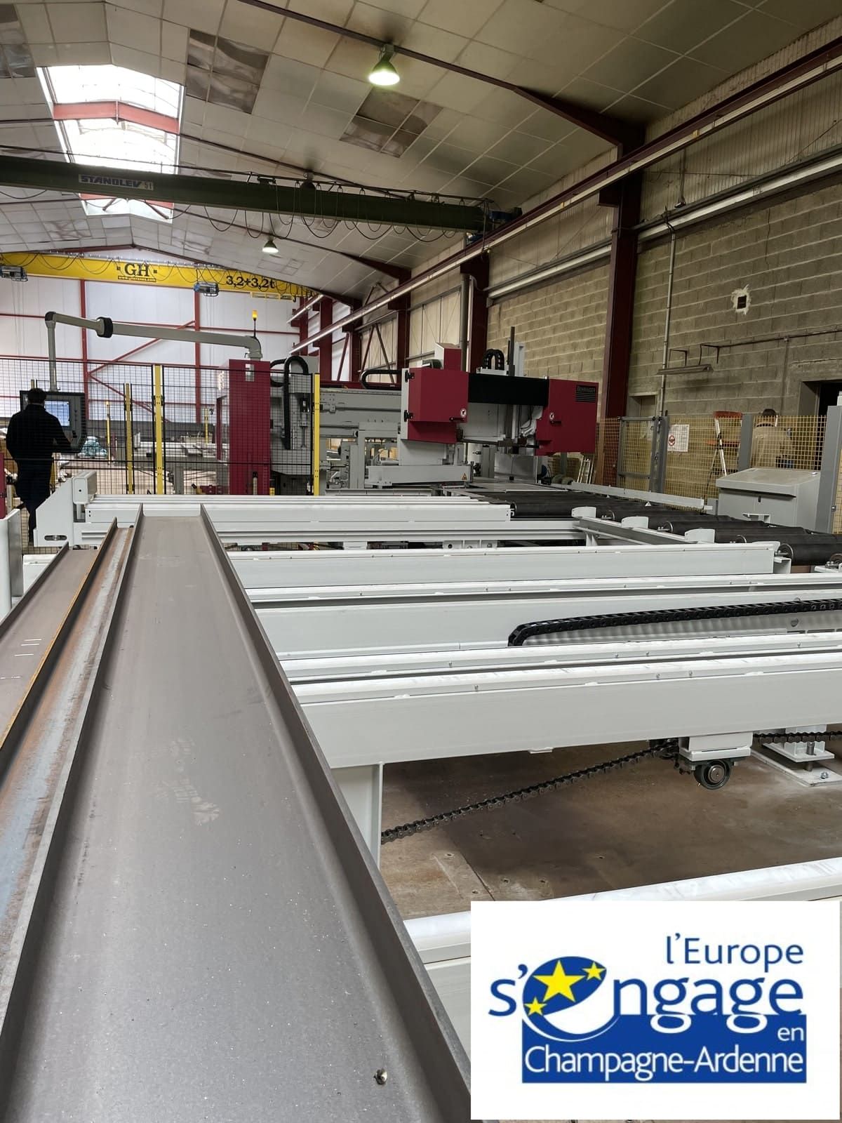 Intérieur d'usine avec machines industrielles. Machines gris métallisé et rouges. Homme en costume noir.