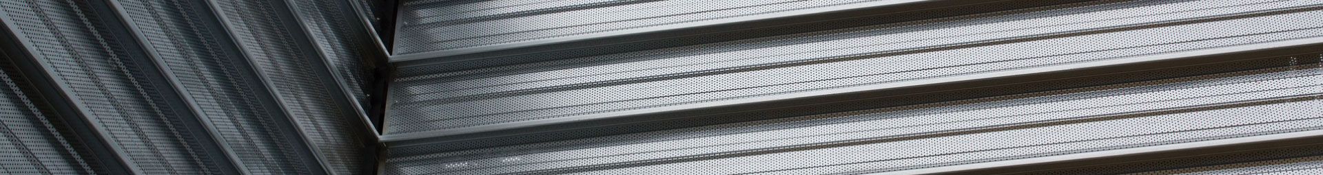 Gros plan sur des surfaces ondulées et à motifs, dans des tons de gris foncé et clair.