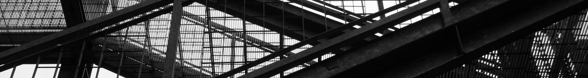 Gros plan en noir et blanc de la structure métallique, avec ses poutres diagonales et ses rambardes.