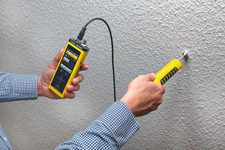 Eine Person hält ein gelbes Gerät, an dem ein Kabel befestigt ist.