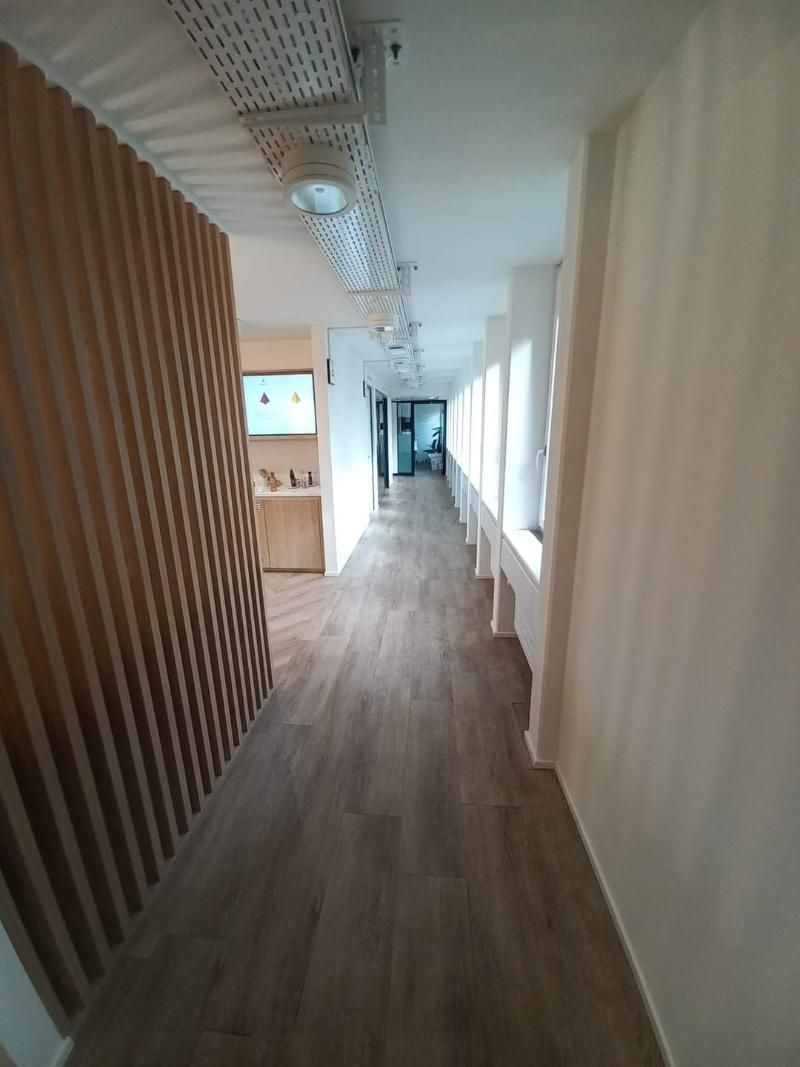 Ein langer Flur mit Holzboden und weissen Wänden in einem Bürogebäude.  Foto von der Popaj GmbH