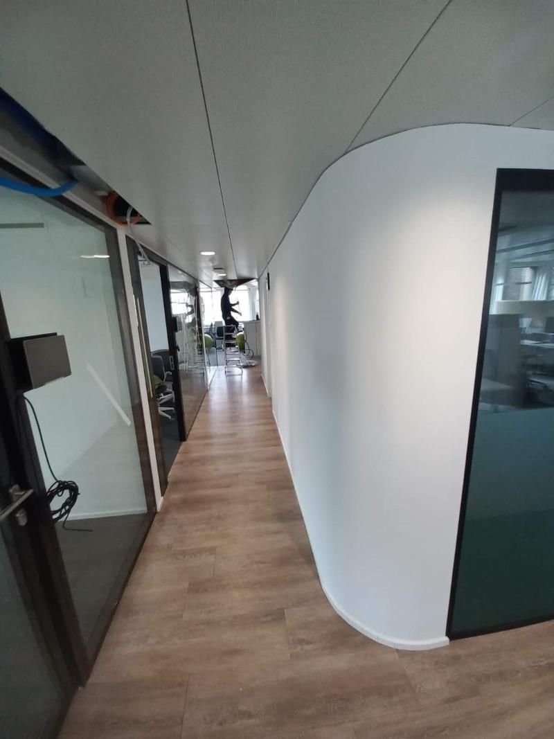 Ein langer Flur mit Holzboden und Glastüren in einem Bürogebäude. Foto von der Popaj GmbH