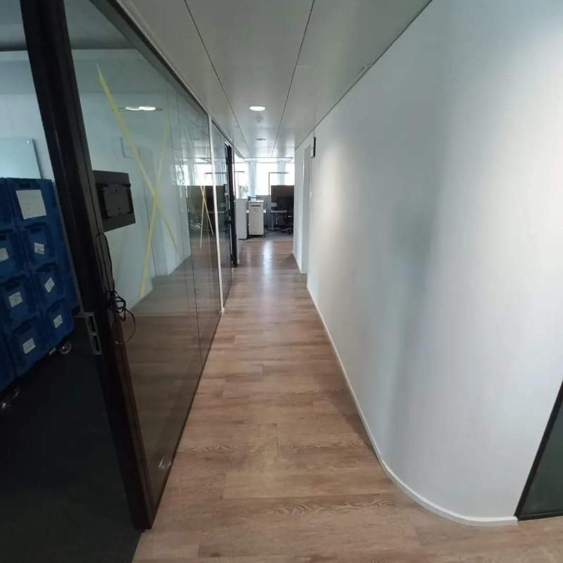 Ein langer Flur mit Holzboden und Glastüren in einem Bürogebäude. Foto von der Popaj GmbH