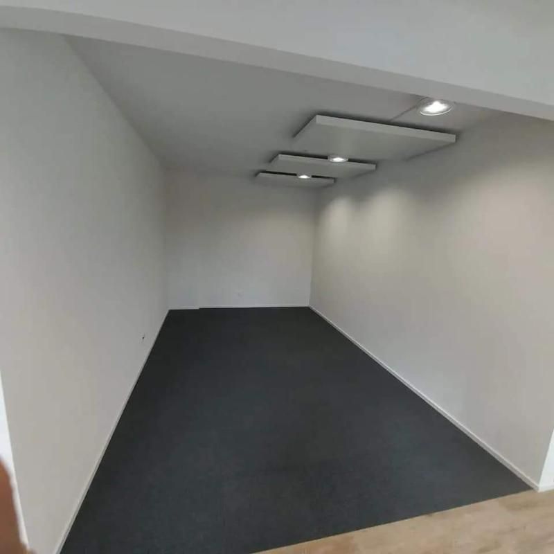 Ein leerer Raum mit schwarzem Teppich und weissen Wänden. Foto von der Popaj GmbH