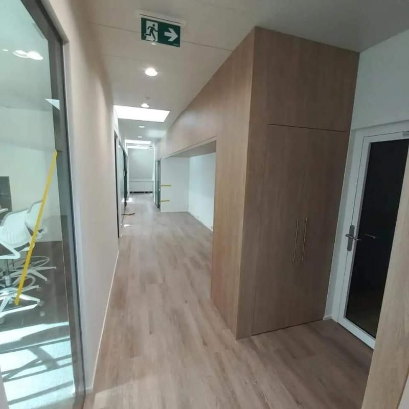 Ein langer Flur mit einem grünen Ausgangsschild an der Decke. Foto von der Popaj GmbH