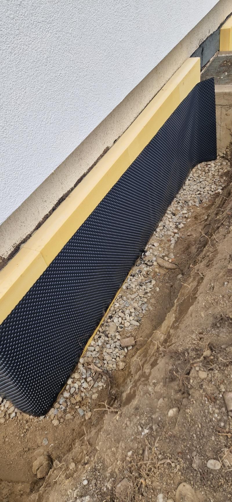 An der Seite eines Gebäudes wird ein Entwässerungssystem installiert. Foto von der Popaj GmbH