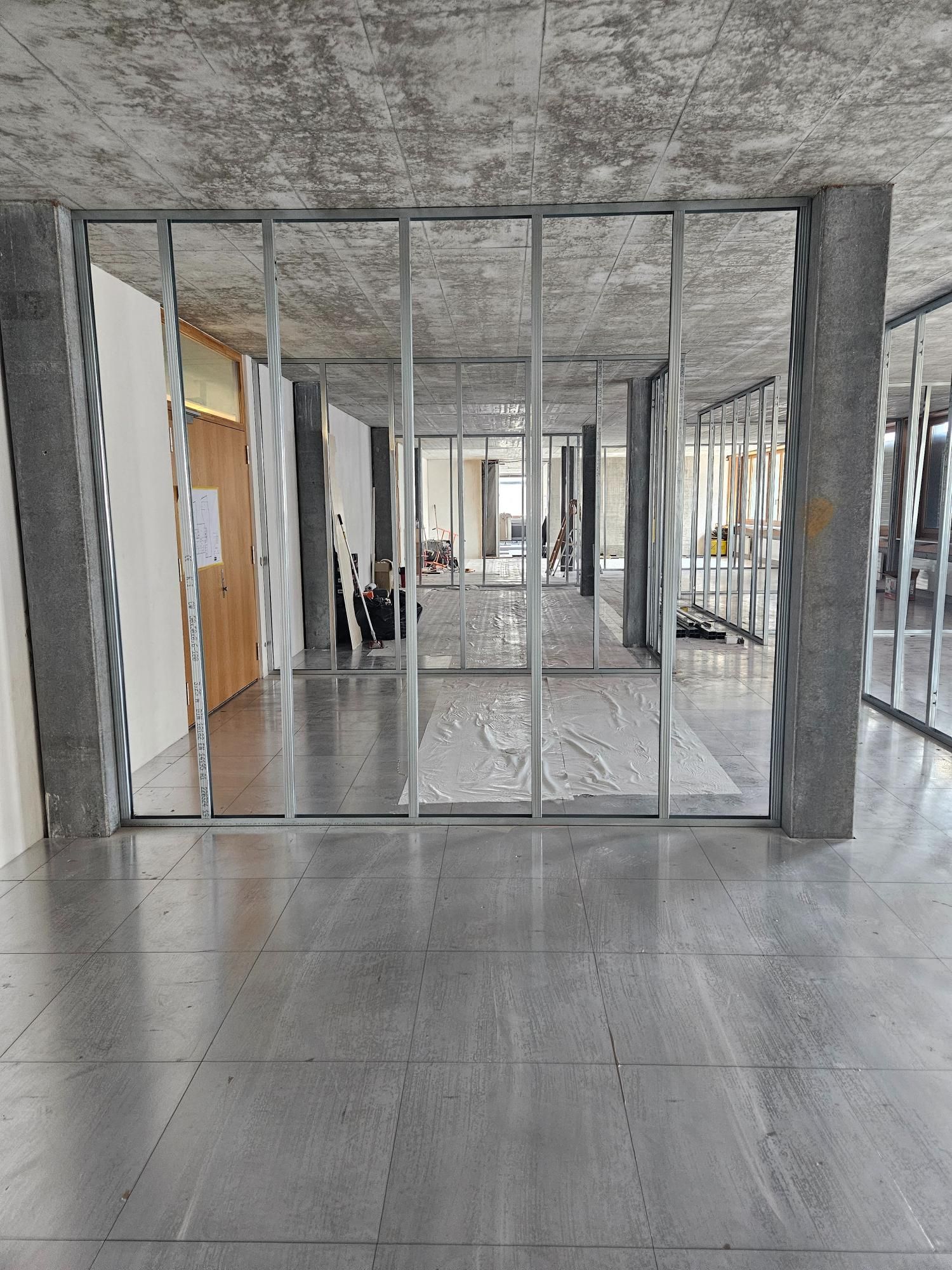 Ein grosser Raum mit vielen Fenstern und einer Betondecke. Foto von der Popaj GmbH