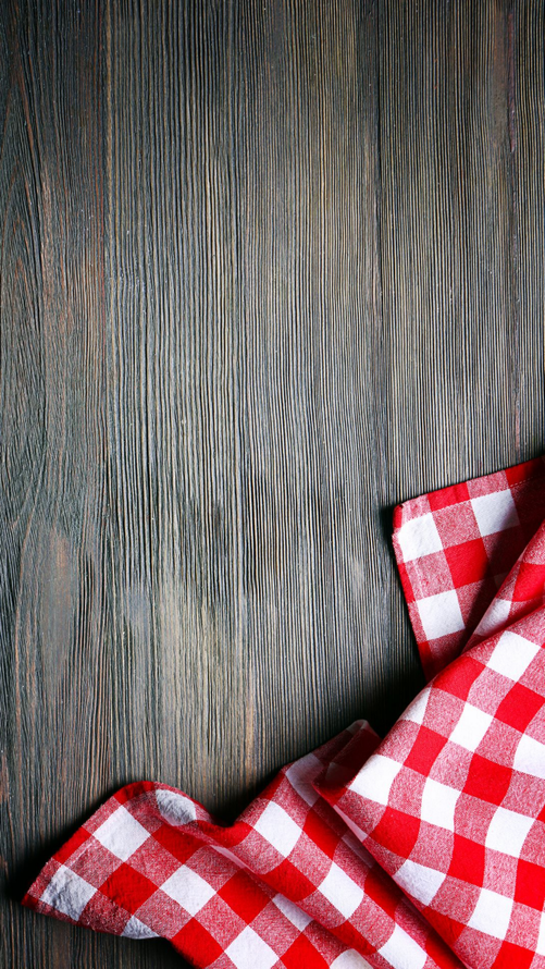 Tissu à carreaux rouges et blancs sur une surface en bois gris-brun patinée.