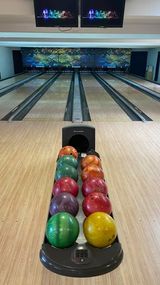 Piste de bowling avec des boules de bowling colorées et plusieurs pistes en vue.