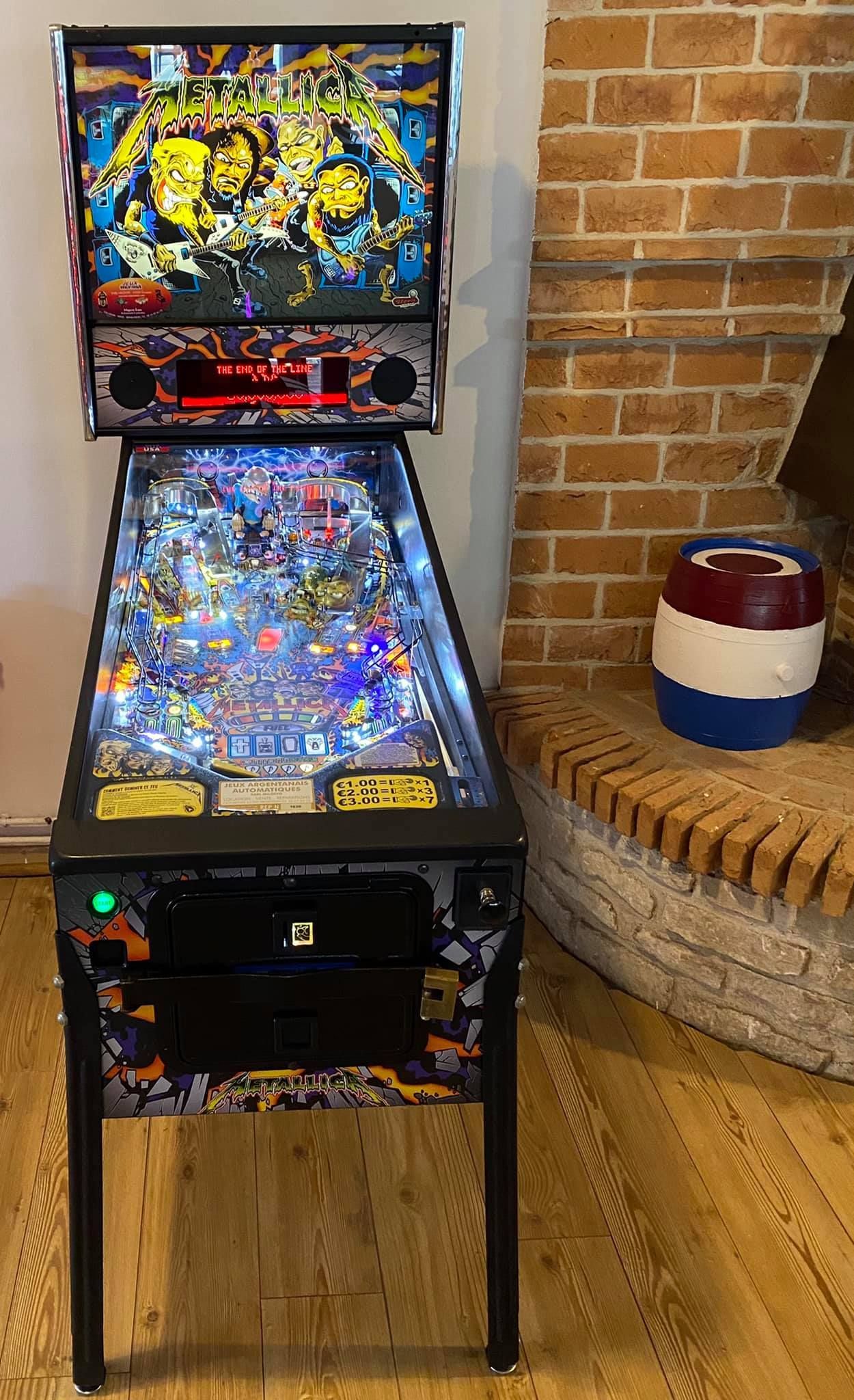 Flipper avec des illustrations colorées, à côté d'un mur de briques et d'un tonneau décoratif.