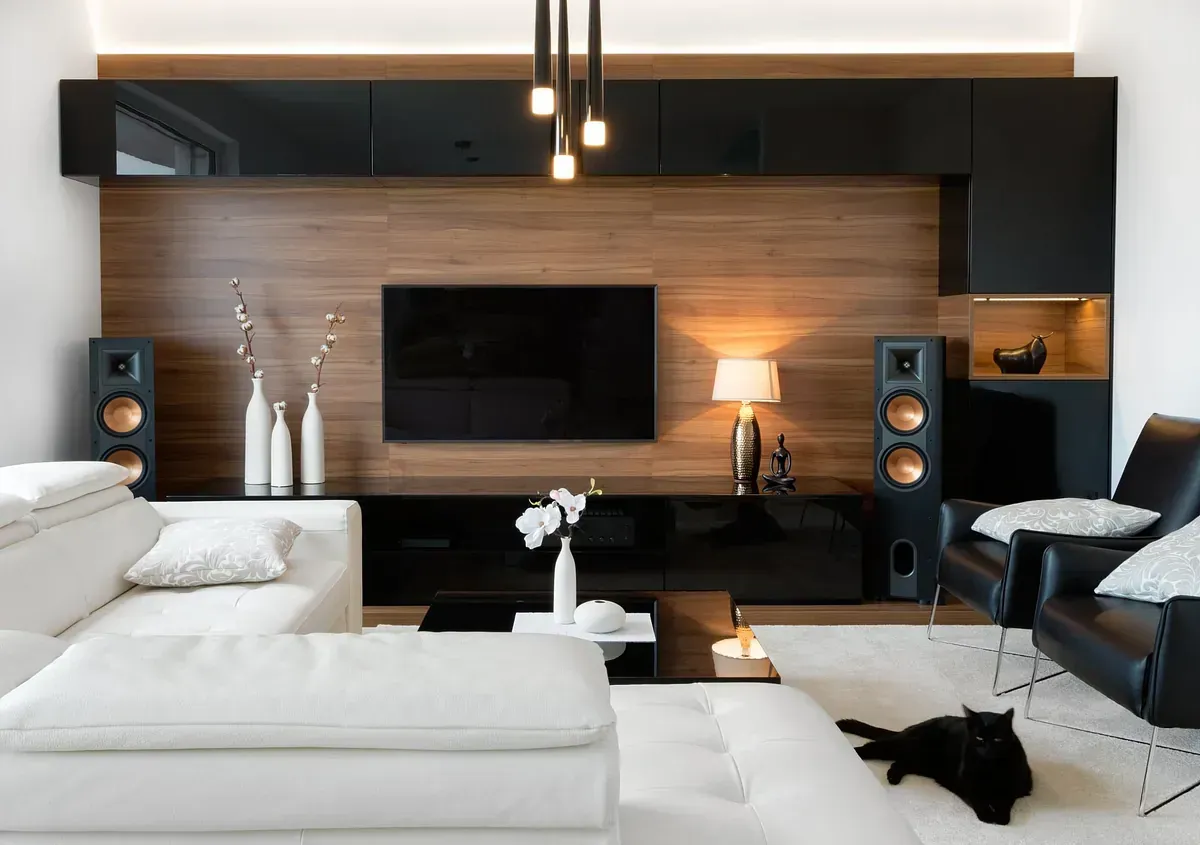 Una sala de estar con sofá, silla, televisión y altavoces.