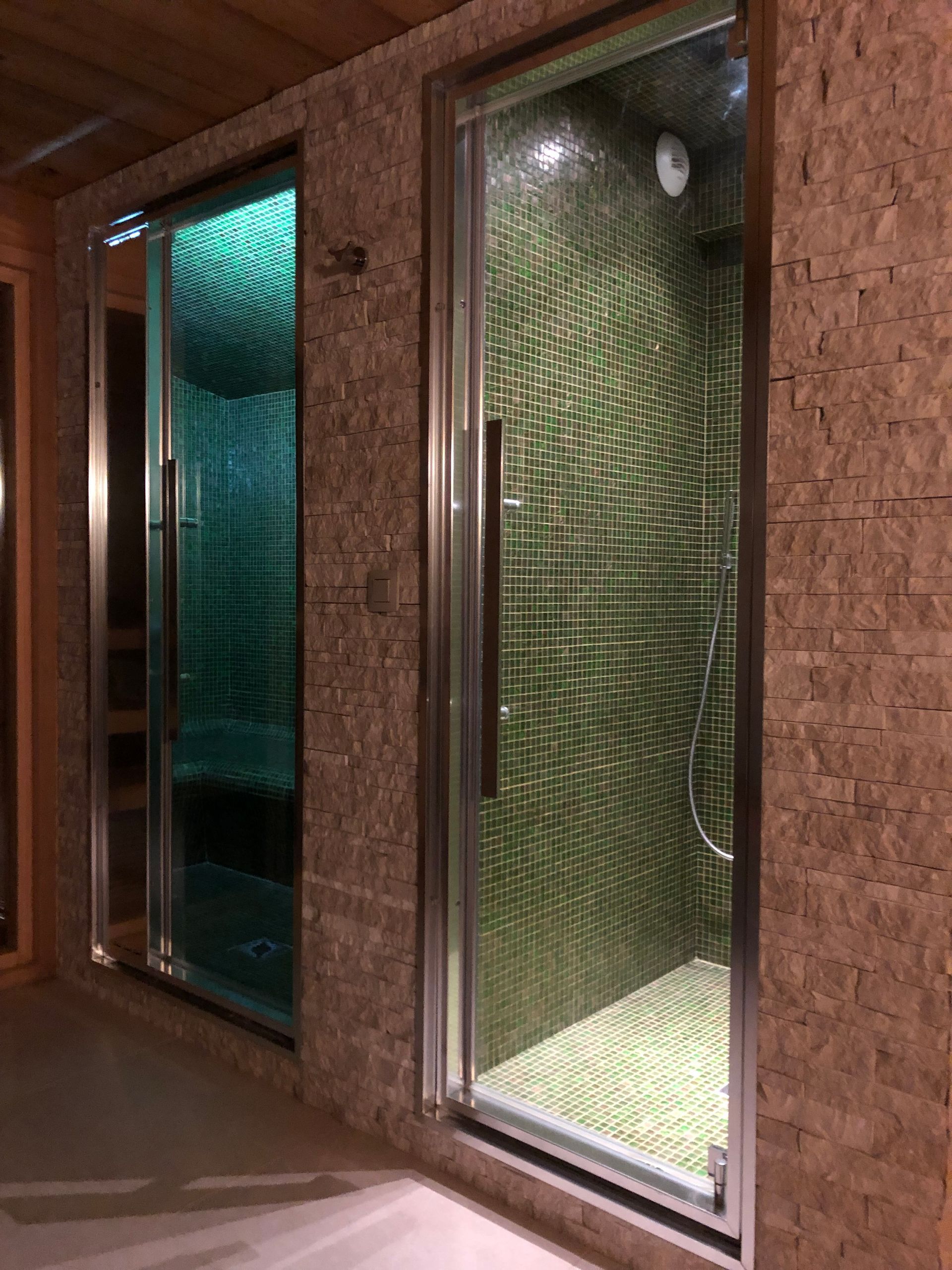 Deux portes de cabine, celle du fond est éclairé par une lumière bleutée