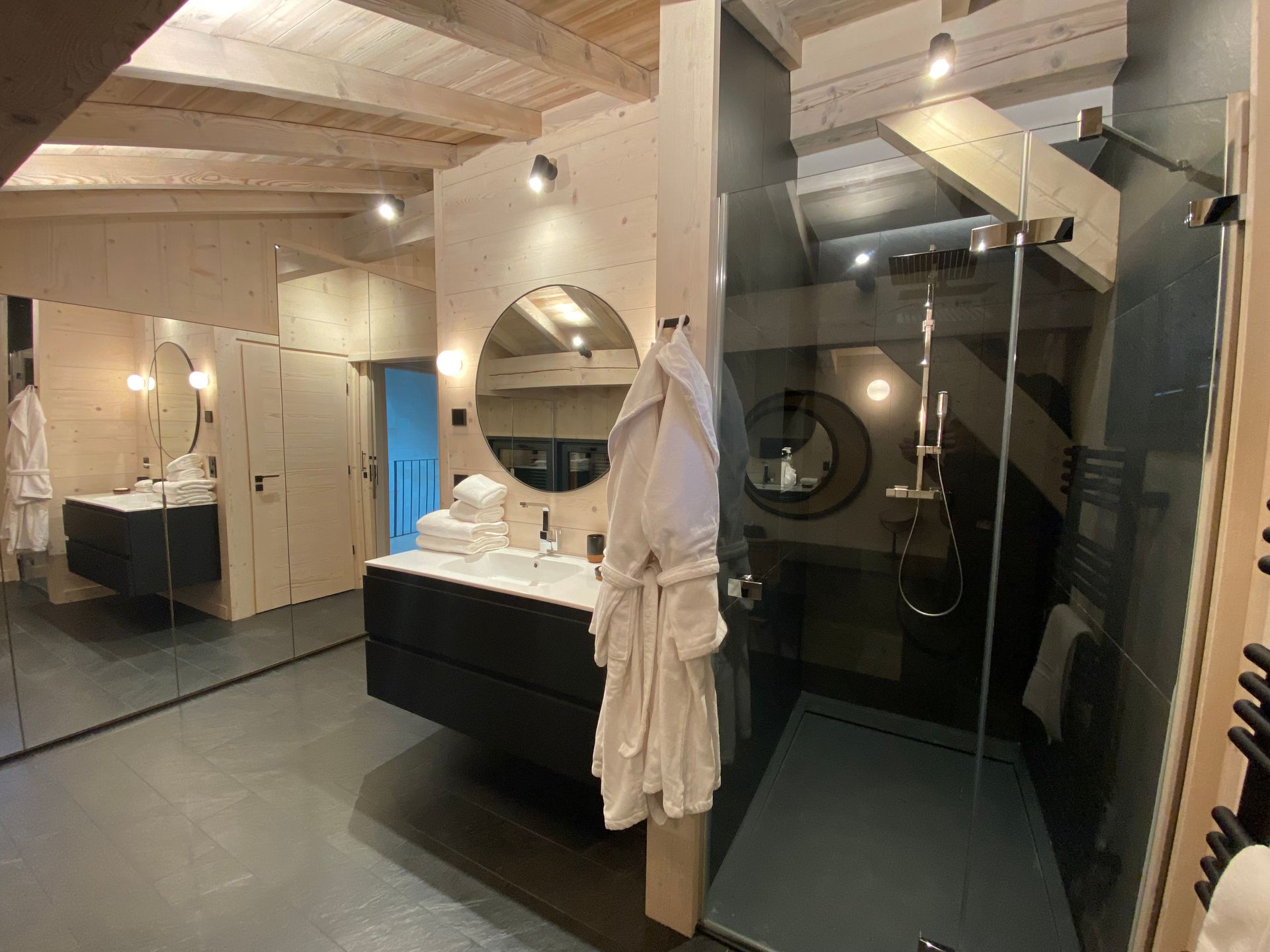 Peignoir blanc accroché au mur d'une cabine de douche dans une salle de bains lumineuse