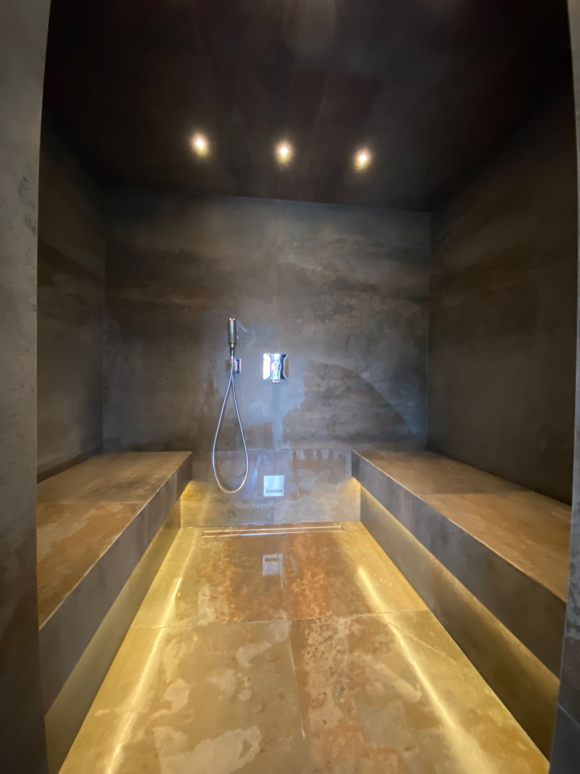 Pièce fermée avec deux grands bancs et une douche au fond