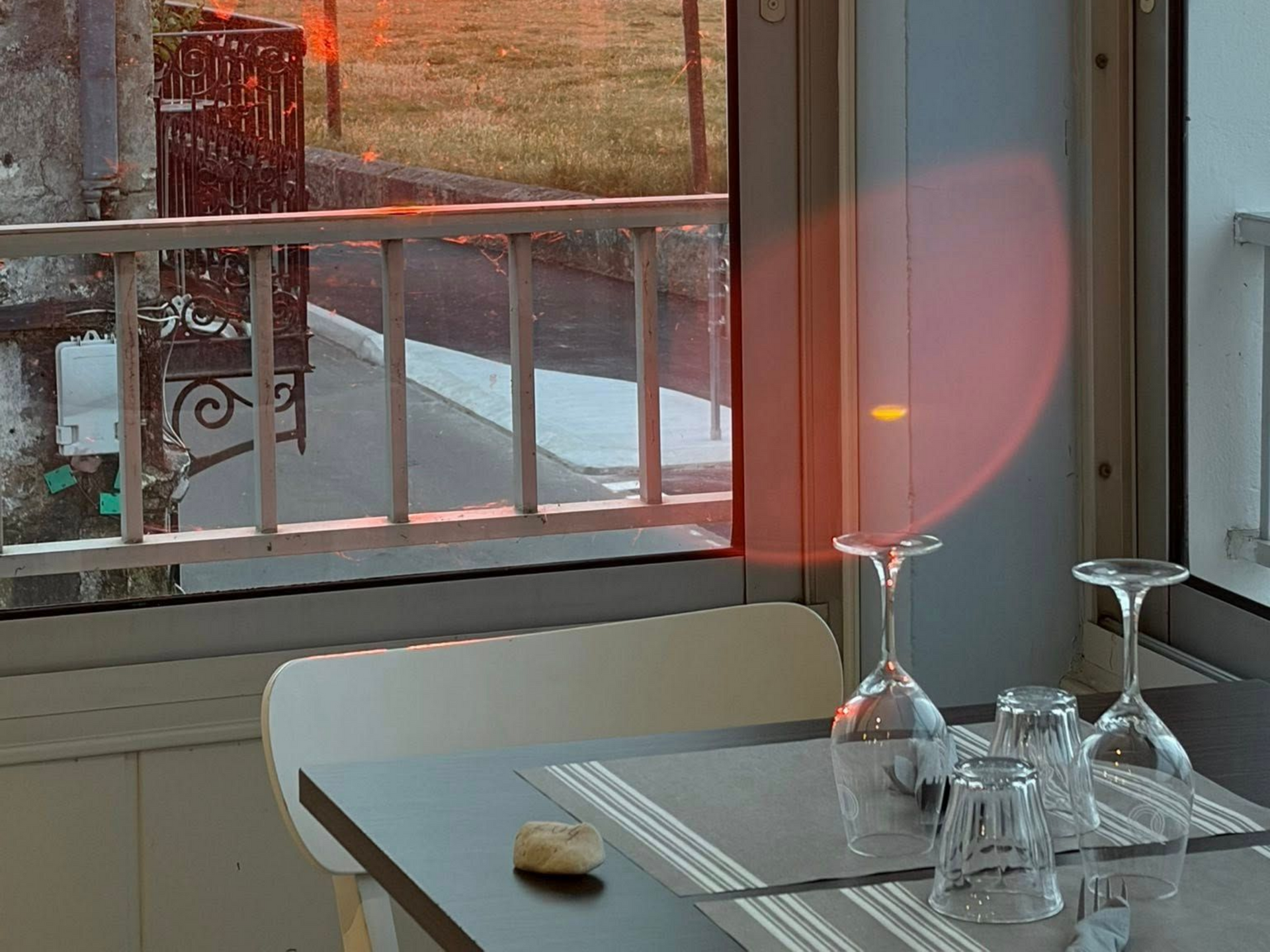 Table à manger près d'une fenêtre aux verres retournés et au reflet rose chaud