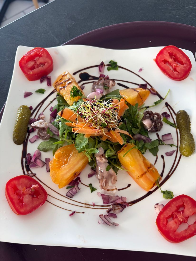 Salade de carottes et de radis sur une assiette rectangulaire blanche, garnie d'herbes et d'un filet de sauce