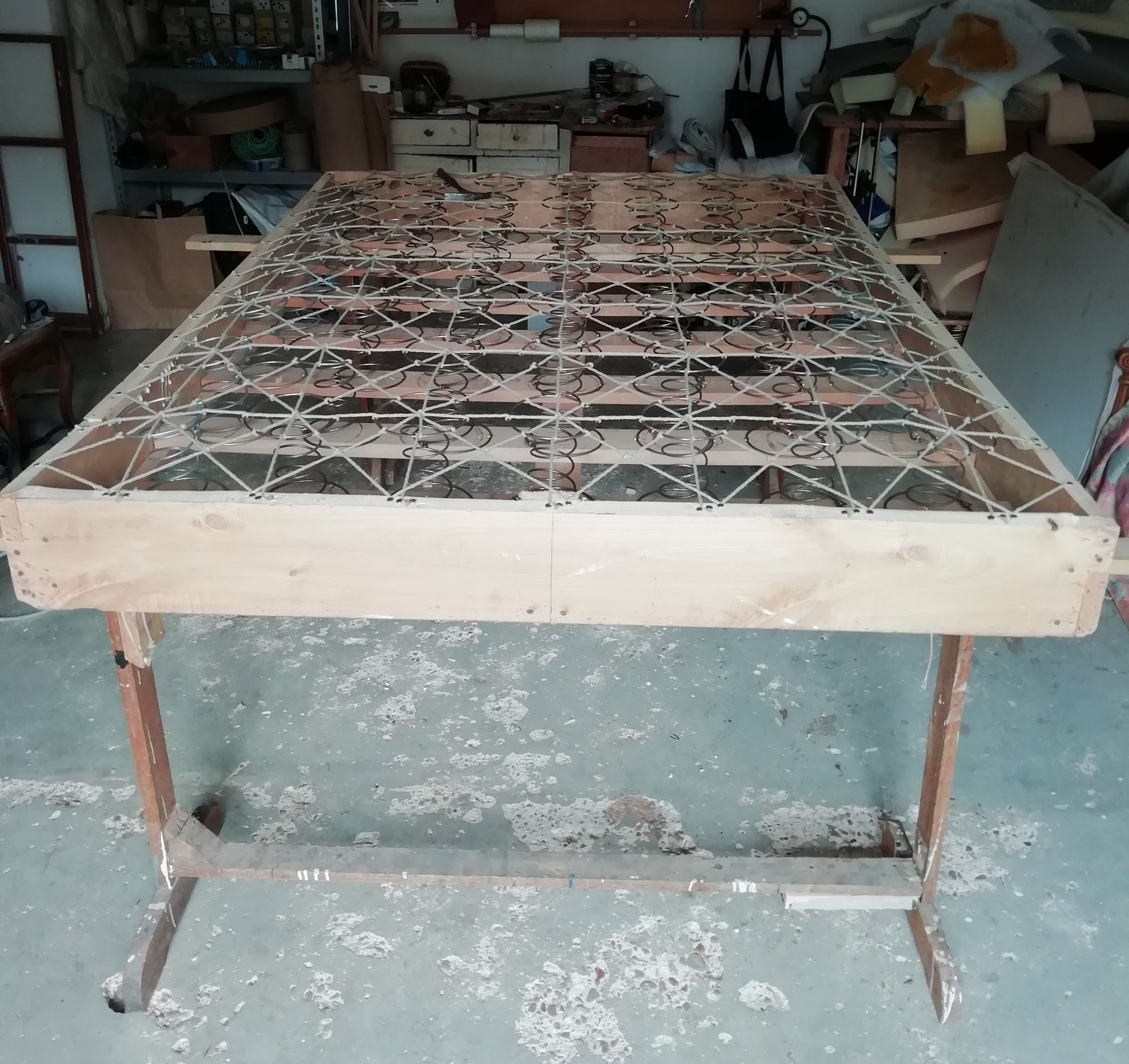 Cadre en bois d'un matelas à ressorts métalliques, sur un établi dans un atelier.