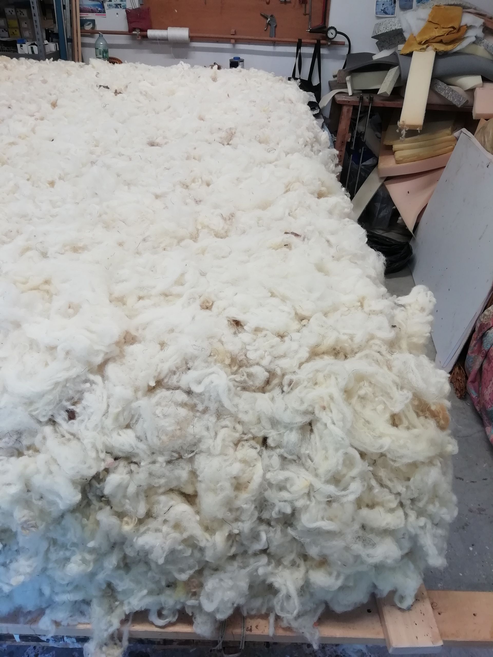 Matelas blanc sur un sommier, avec des oreillers, dans une chambre.