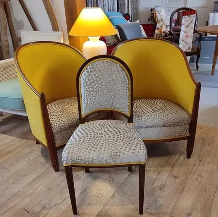 Ensemble de meubles rembourrés jaunes et gris : causeuse et fauteuil. Une lampe allumée est posée sur la causeuse.