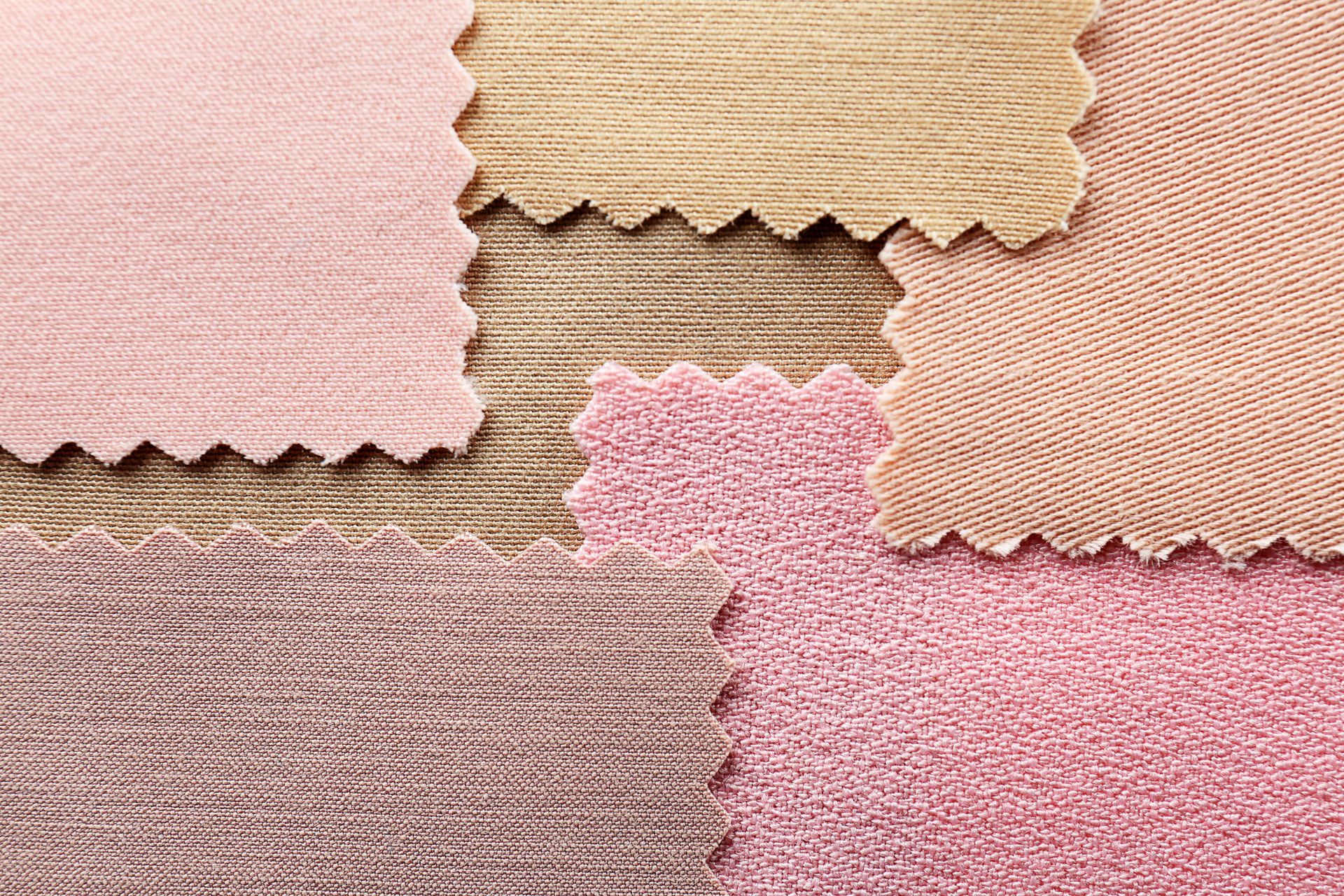Échantillons de tissu de textures et de nuances de rose et de beige variées.
