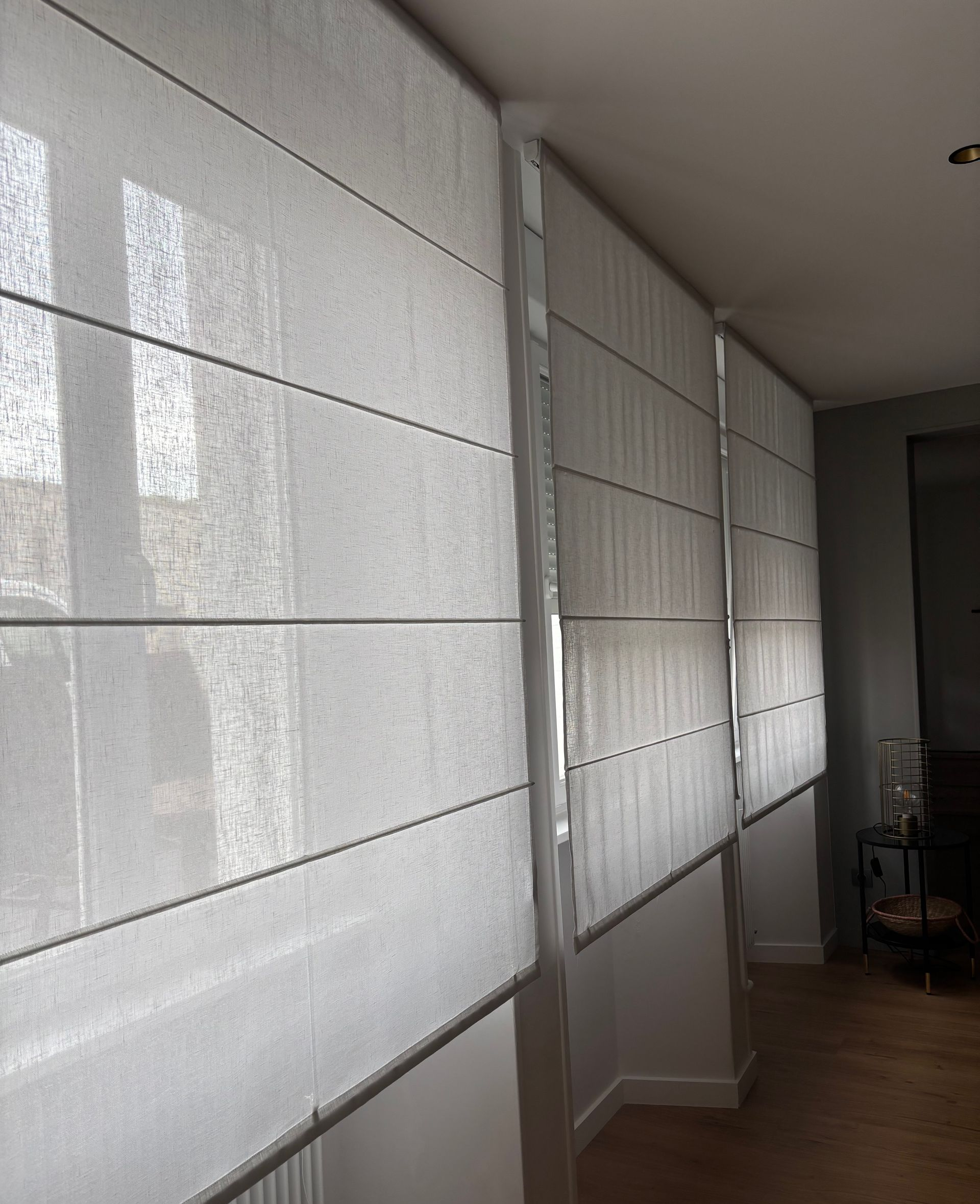 Stores horizontaux beiges recouvrant partiellement une fenêtre.