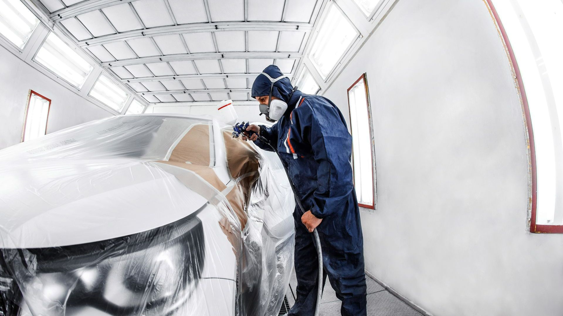Ouvrier peignant une voiture blanche dans un garage