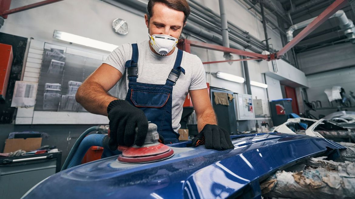 Technicien automobile rectifiant une pièce de carrosserie automobile
