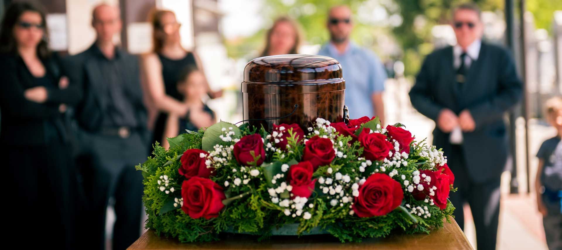 Une urne entourée de fleurs en fond une famille