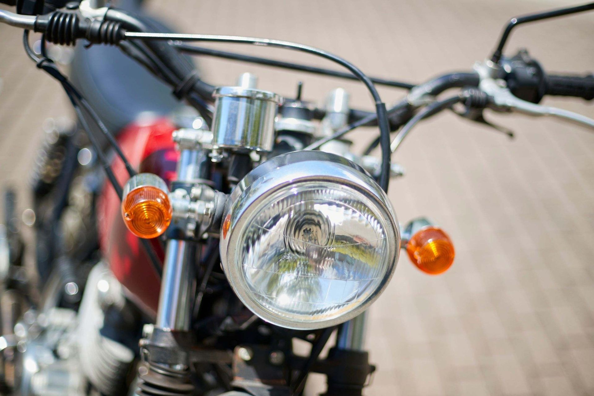 Un primer plano de un faro de motocicleta en un camino de ladrillos.