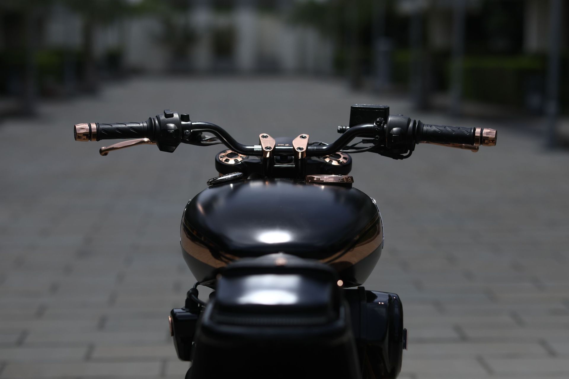 Una motocicleta negra y dorada está estacionada en una acera.