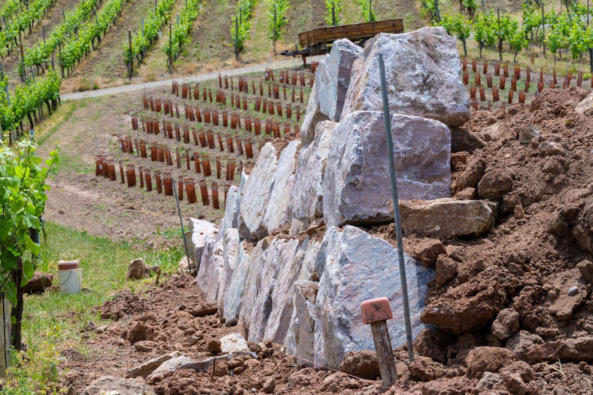 Mur de soutènement en pierre en construction à côté d'un coteau viticole.