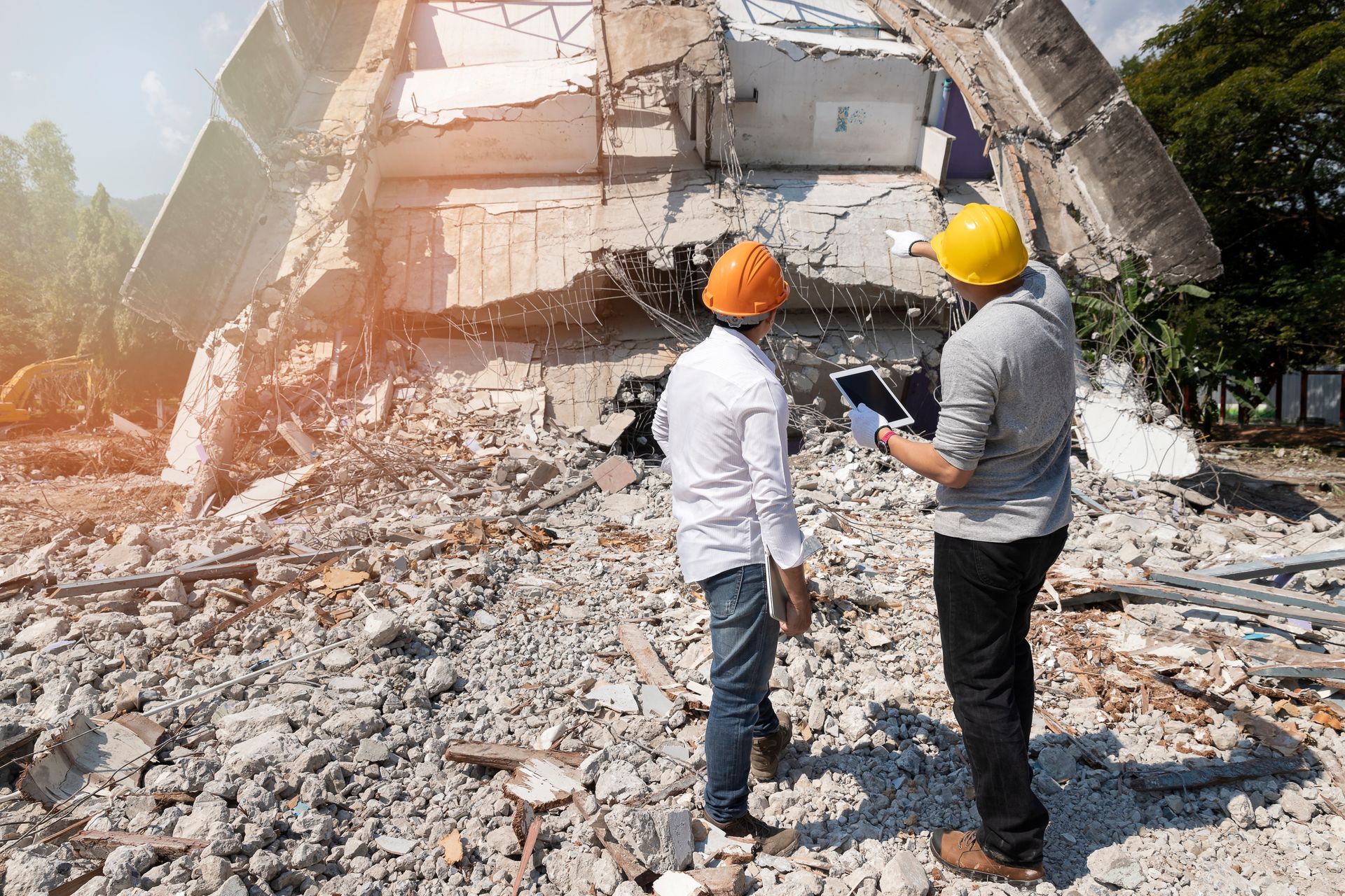 Deux ouvriers casqués inspectent un chantier de démolition.