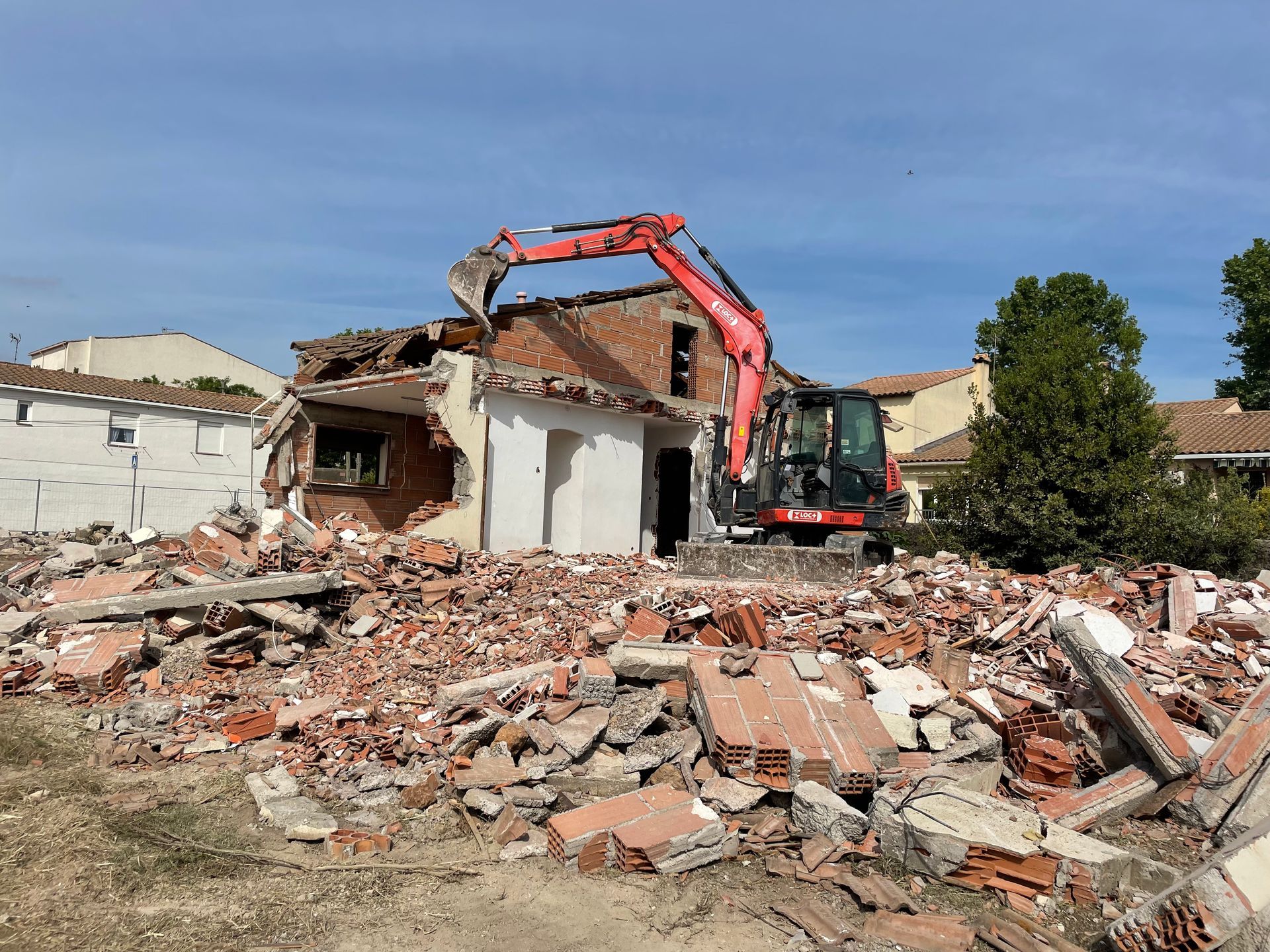 Une pelleteuse orange démolit un bâtiment.