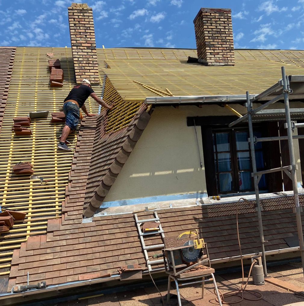 Un ouvrier pose des tuiles sur la charpente d'un toit