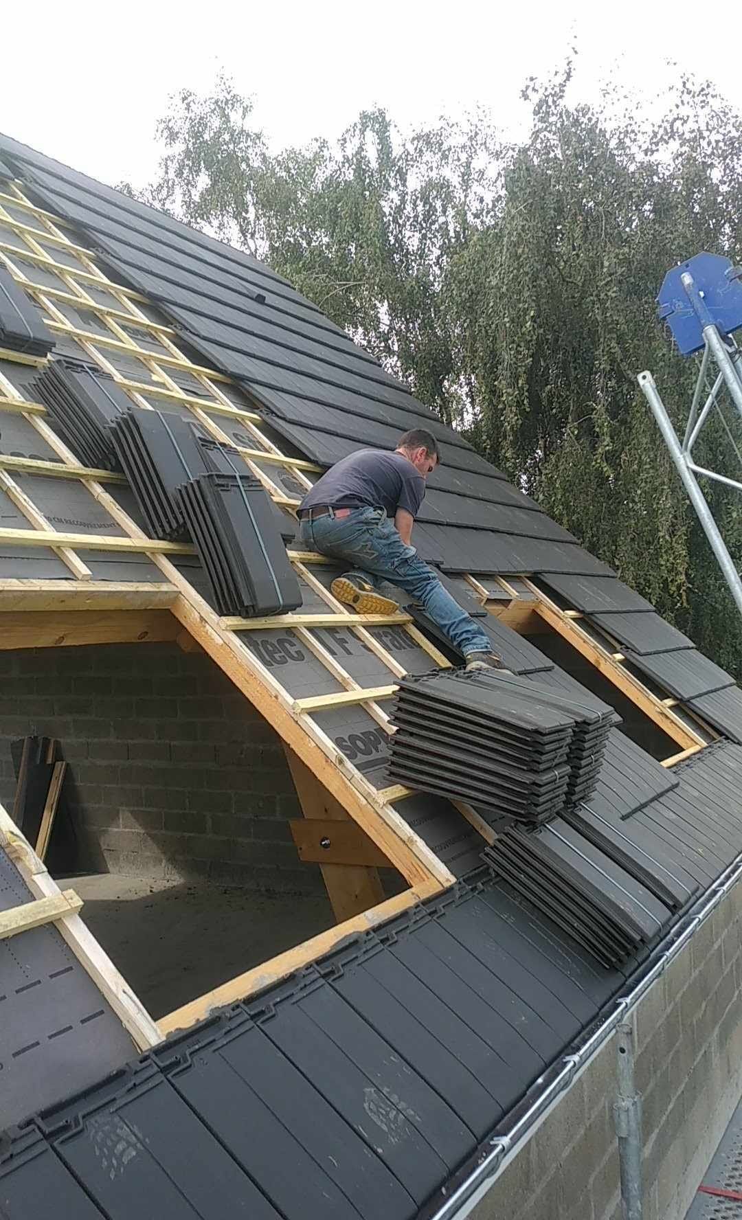 Un ouvrier pose des ardoises sur un toit