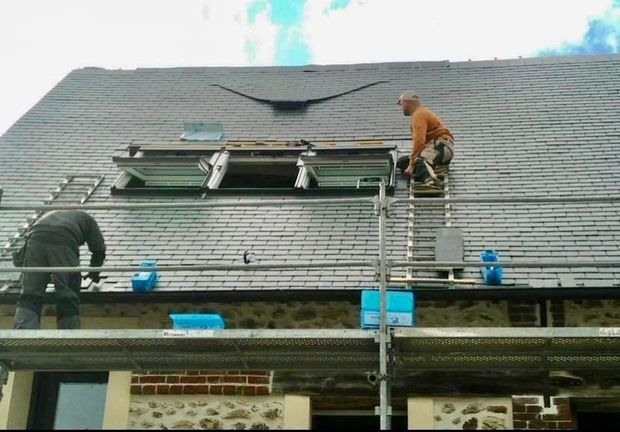 Deux ouvriers travaillent sur un toit en ardoise