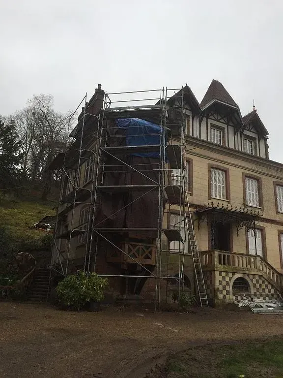 Un échafaudage devant une tour en tuile d'une maison en cours de rénovation