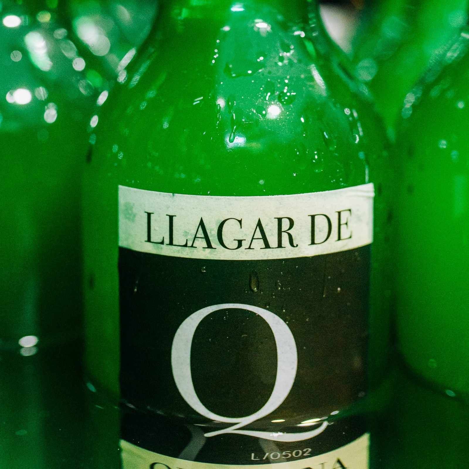 Primer plano de una botella verde con la etiqueta “LLAGAR DE O”, con una etiqueta oscura y letras blancas.