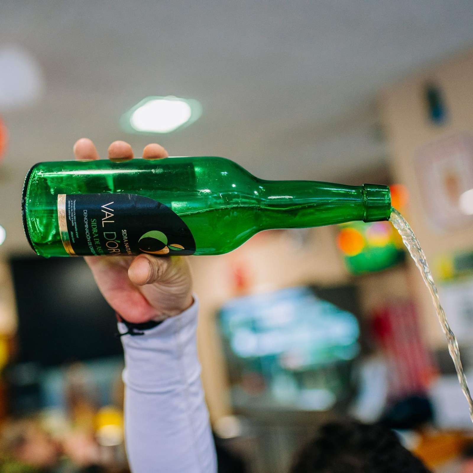 Verter a mano agua con gas de una botella de vidrio verde en un vaso.