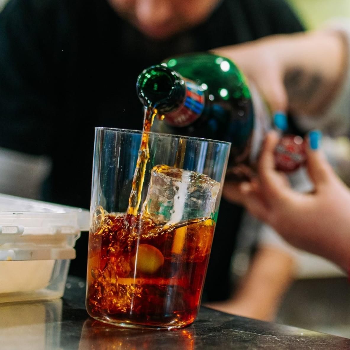 Verter refresco en un vaso con hielo en una mesa.