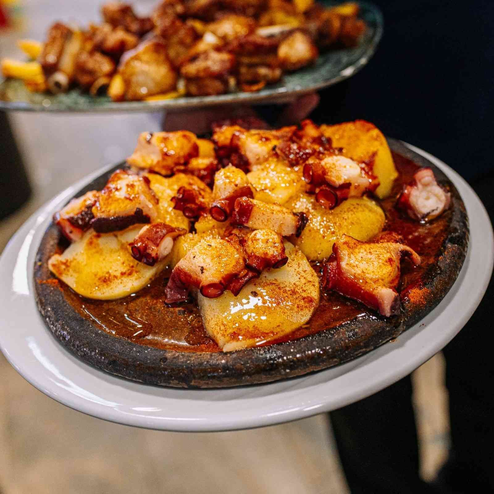 Dos platos de comida dorada cubiertos con nueces picadas sobre una mesa oscura.