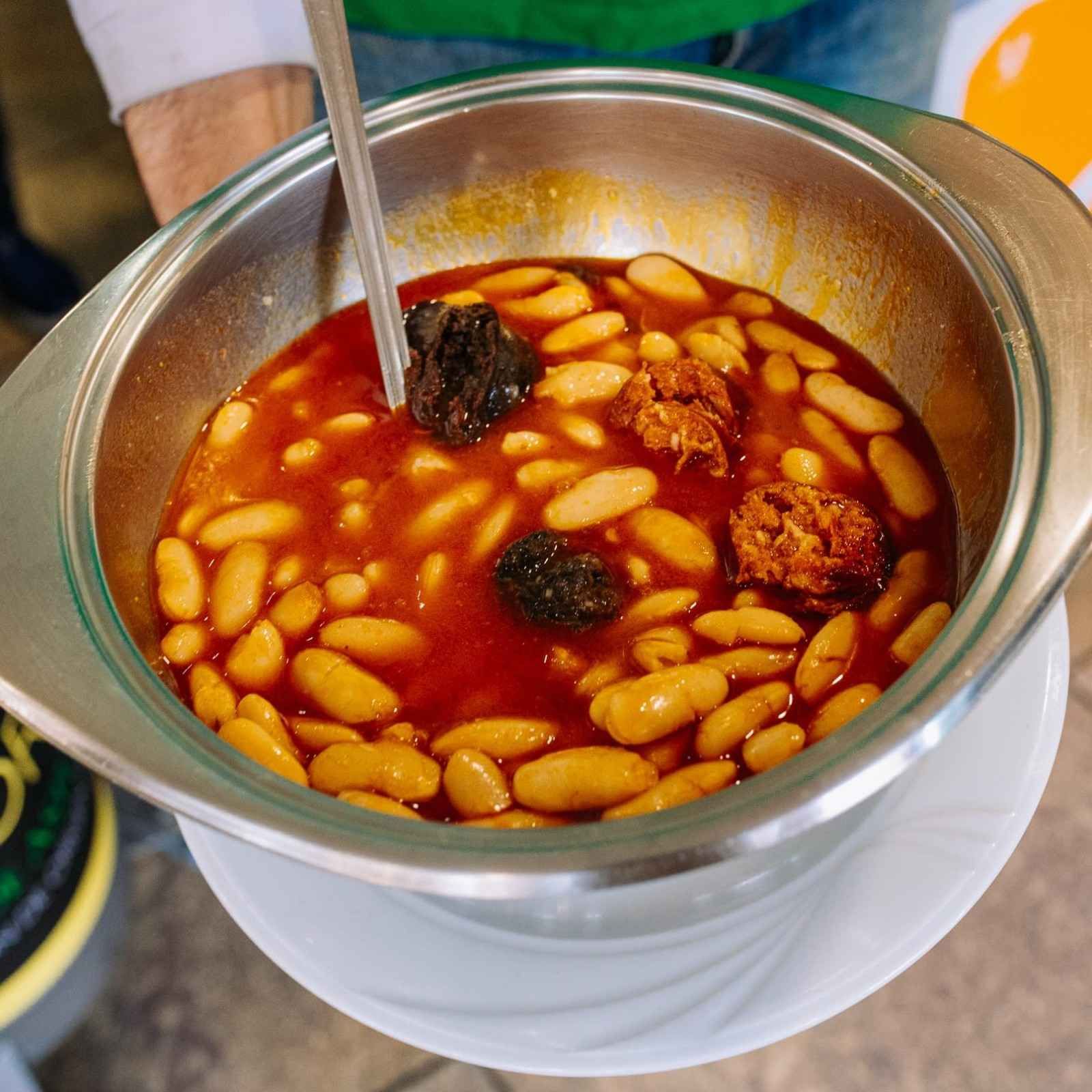 Bol de estofado de frijoles rojos con frijoles blancos y albóndigas, removido con una cuchara.
