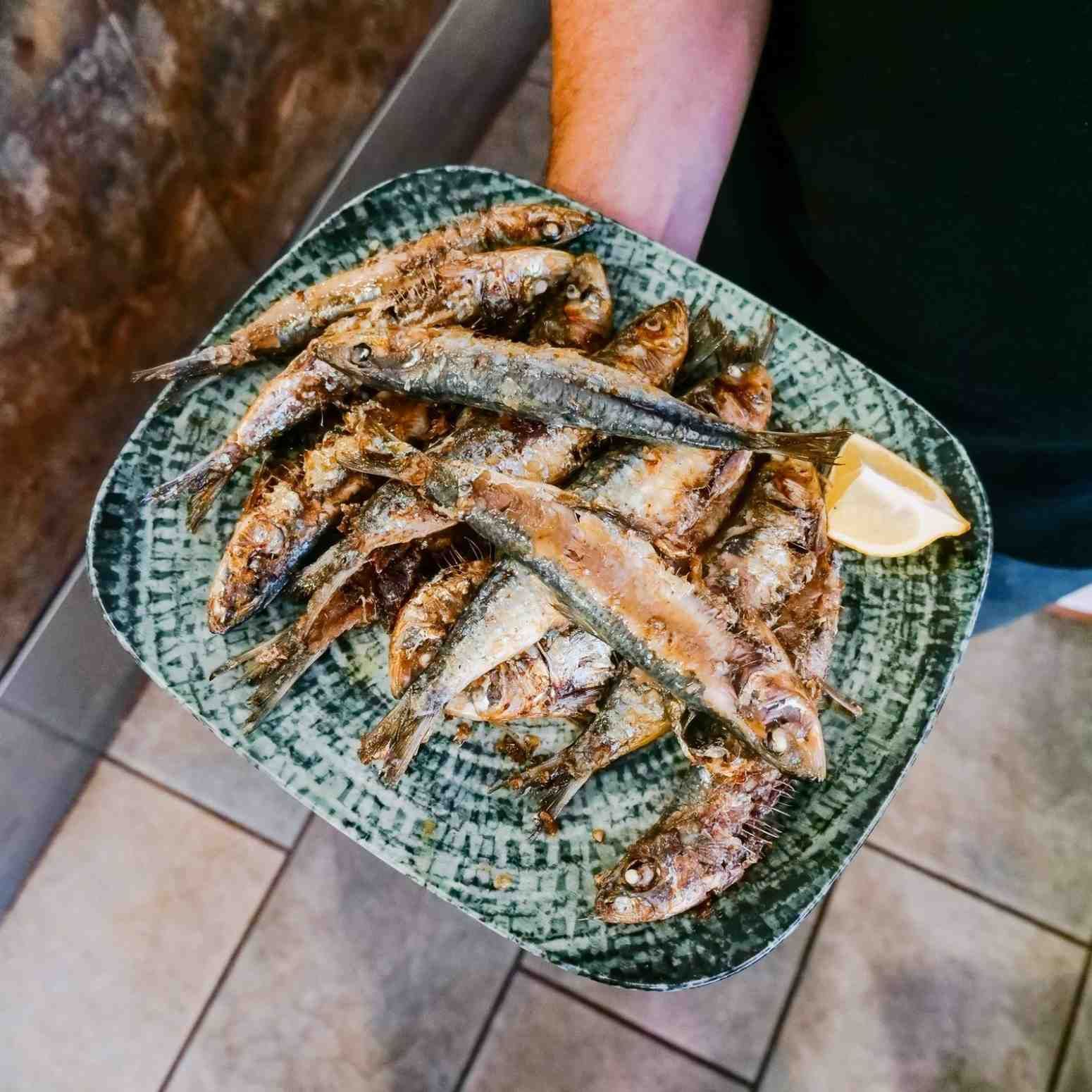 Pescado a la parrilla dispuesto en un plato con estampado verde con una rodaja de limón.