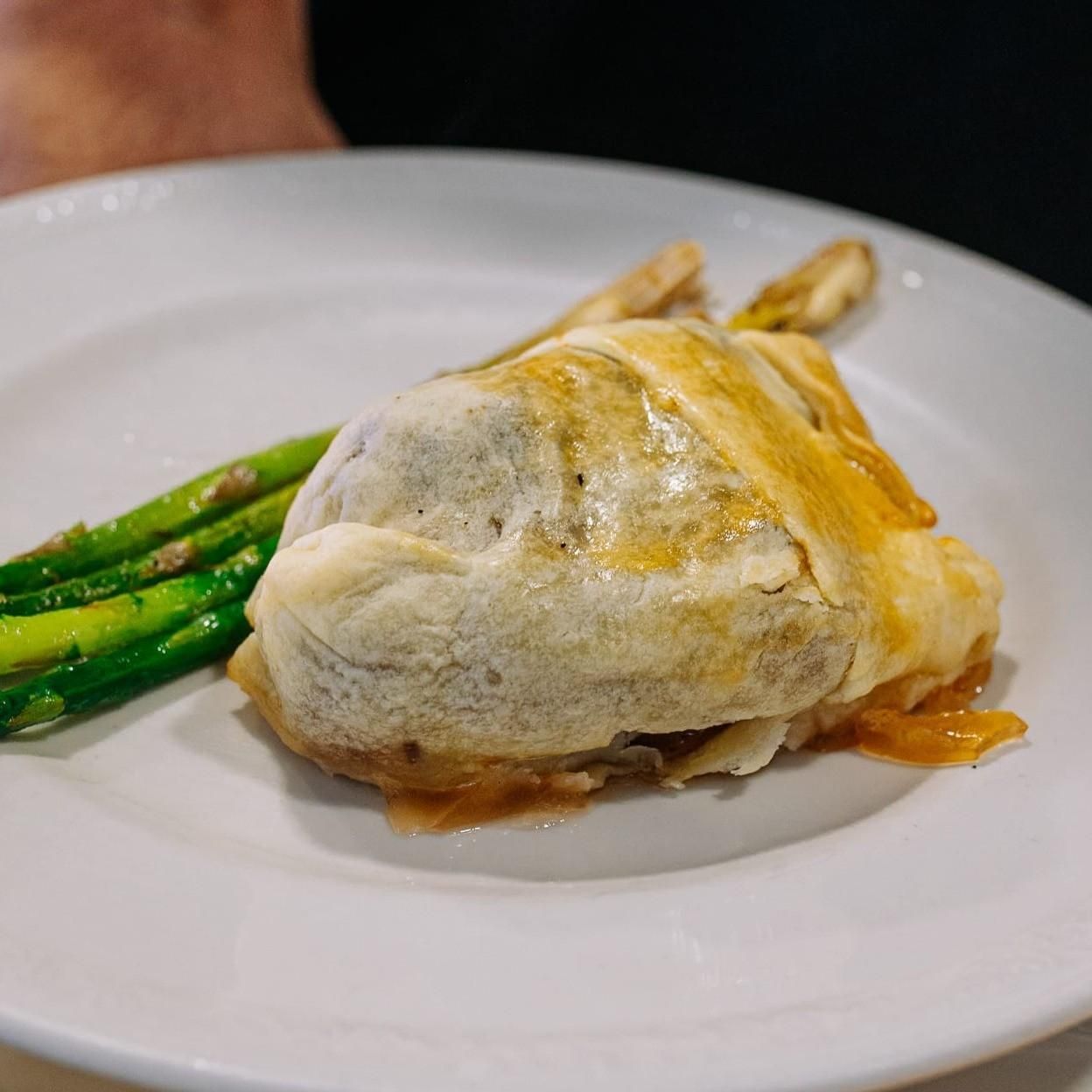 Pechuga de pollo asada con espárragos servida en un plato blanco.