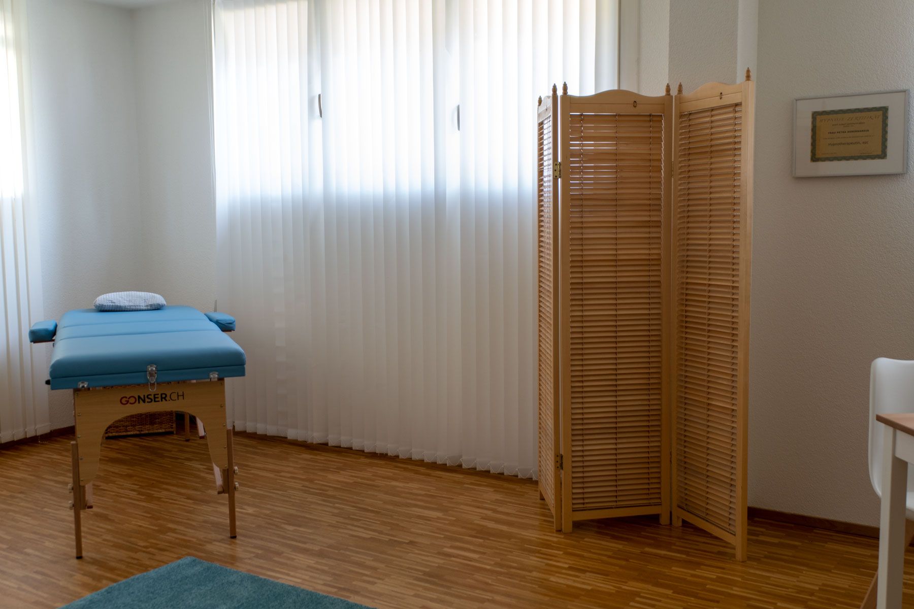 Ein Raum mit einem Massagetisch und einer Holzwand.