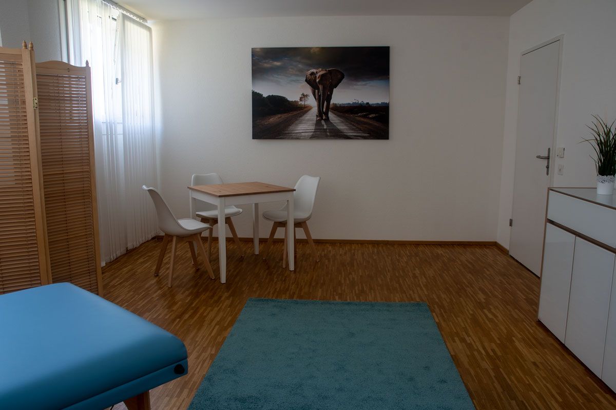 Ein Raum mit einem Tisch und Stühlen und einem Bild eines Elefanten an der Wand