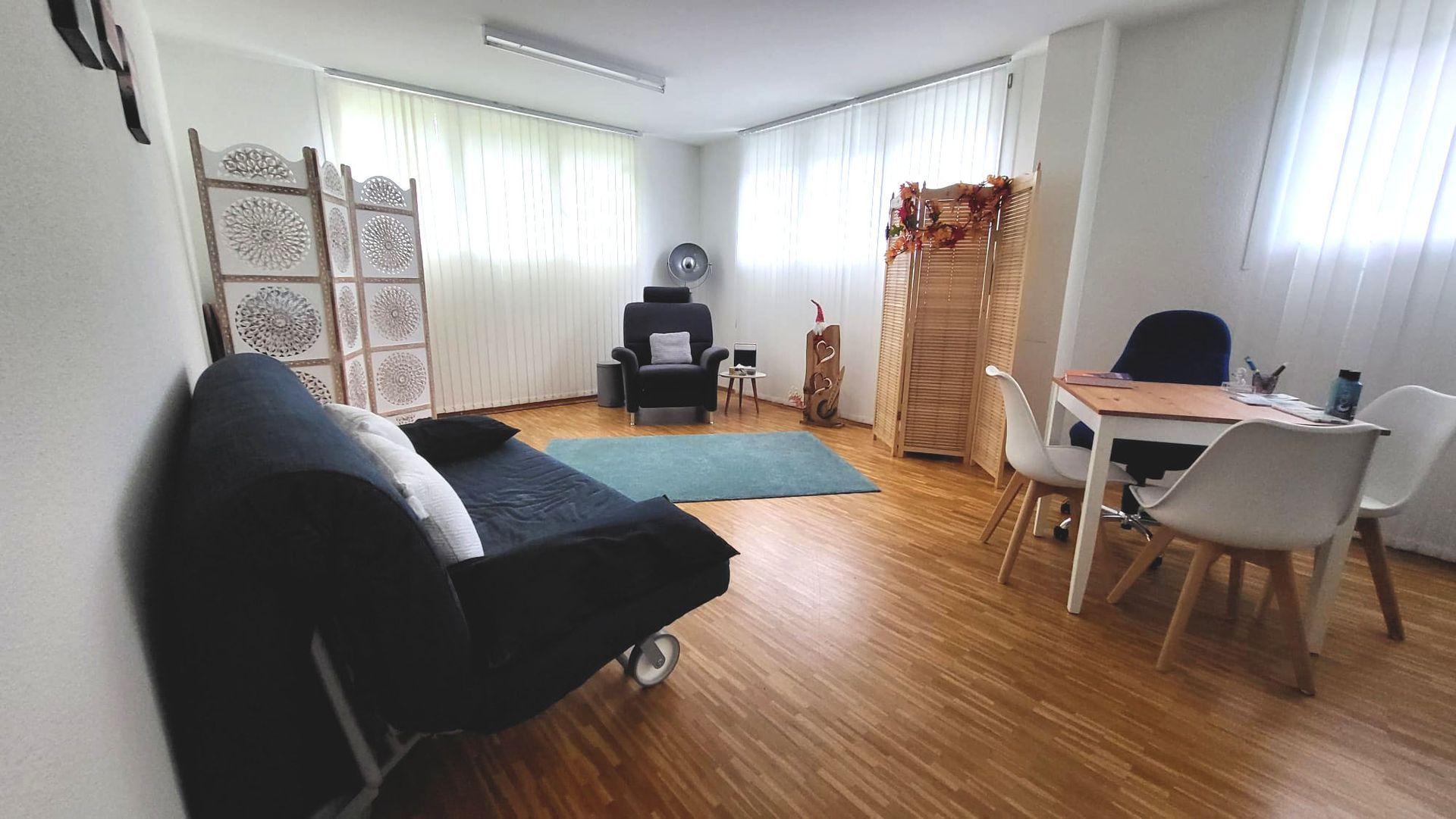 Ein Wohnzimmer mit Couch, Sessel, Tisch und Stühlen.
